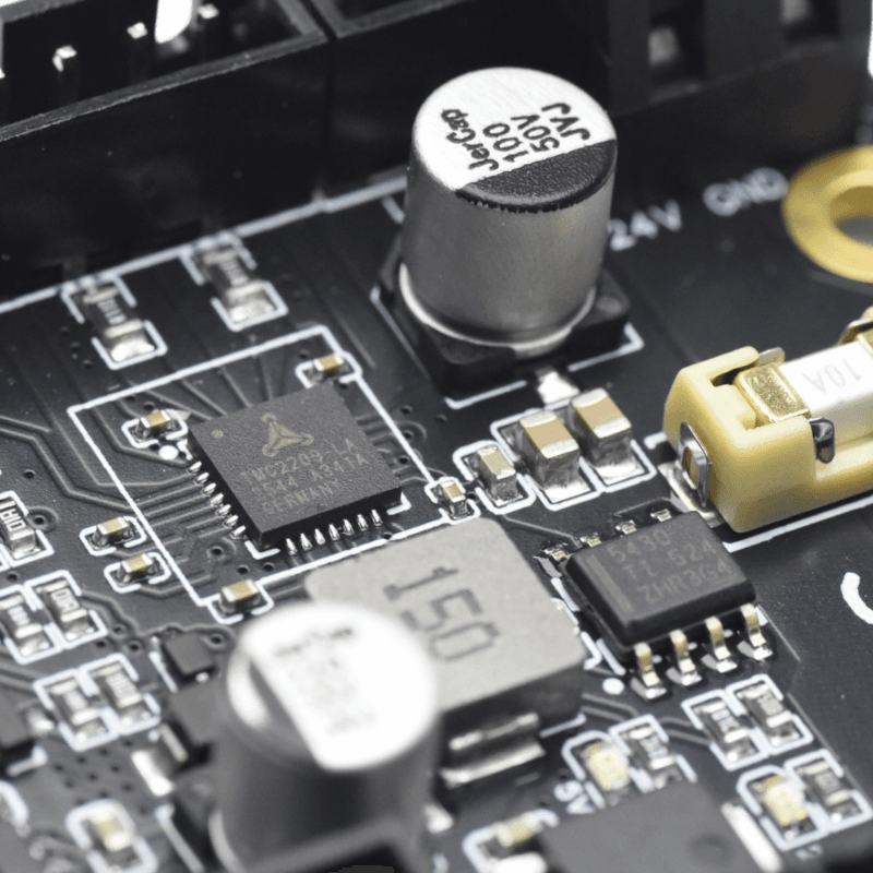 Close-up of a circuit board featuring a TMC2209 stepper motor driver chip, capacitors, and surface-mount components