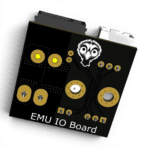 3D render of the EMU IO Board, a black circuit board with gold contact points and an emu logo